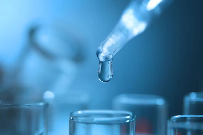 Dropper releasing a water sample into a test tube for water testing